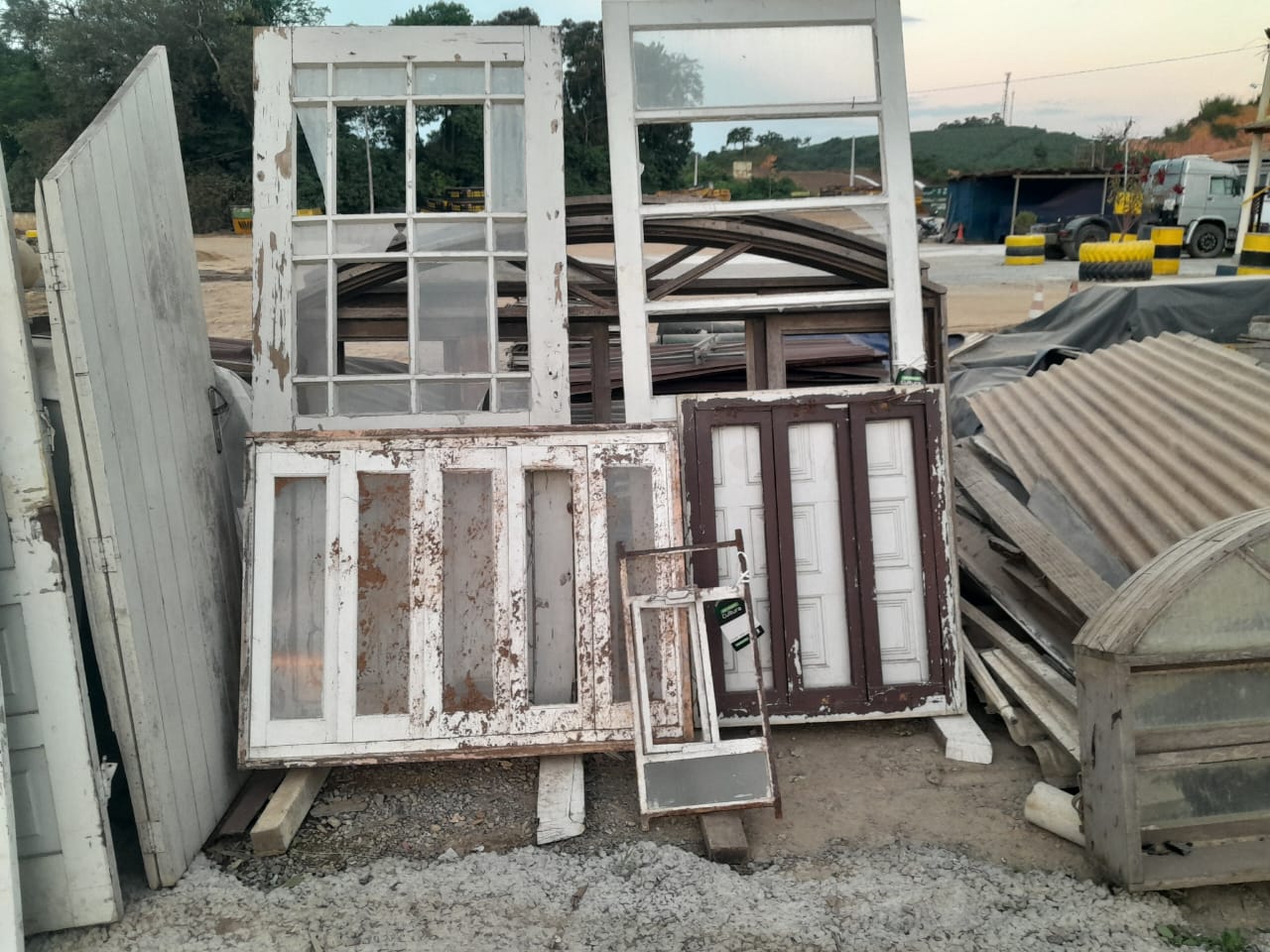 Estoque de materiais reaproveitados: portas, janelas antigas e telhas de fibrocimento dispostas no pátio da loja.