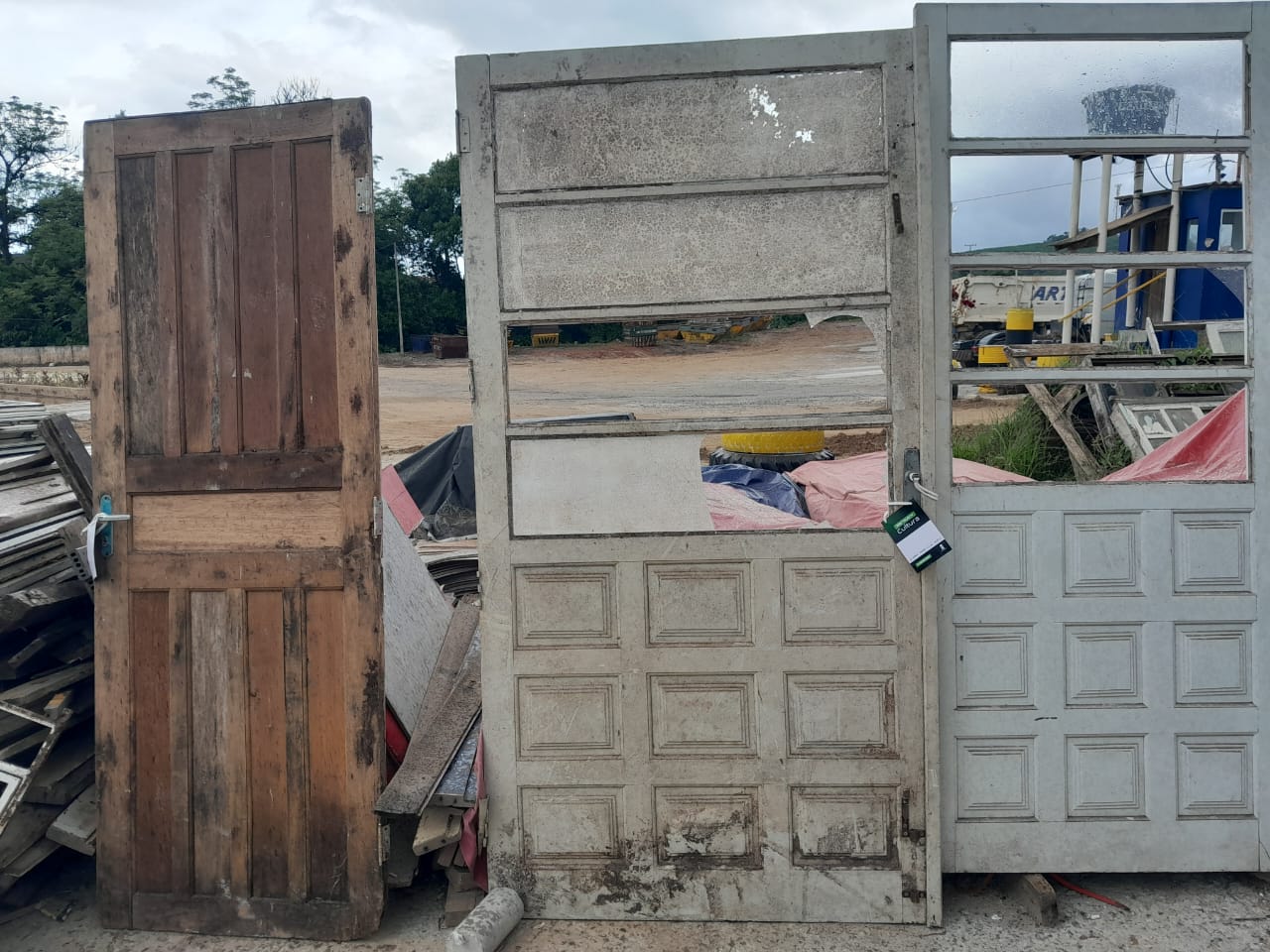 Portas de demolição (madeira maciça e almofadada) disponíveis no pátio, exemplo típico do estoque de materiais reaproveitados.
