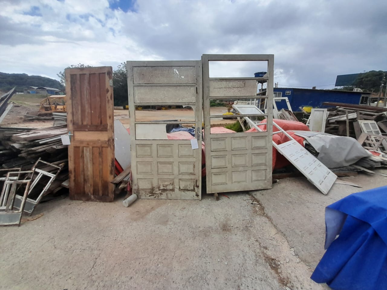 Pátio com portas, janelas e materiais de construção recuperados à venda para reutilização.