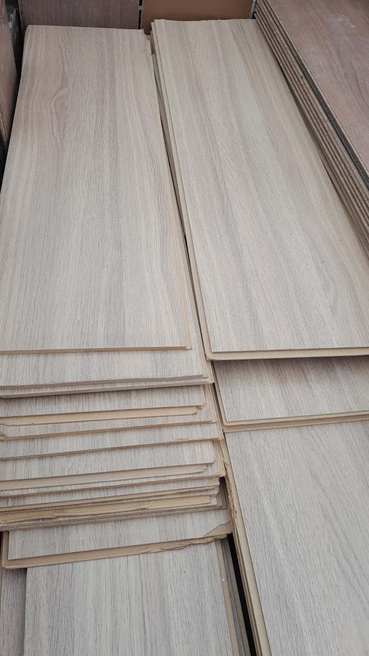 Pilhas de chapas de madeira (compensado/MDF com acabamento amadeirado) estocadas, prontas para revenda como material de construção reutilizado.