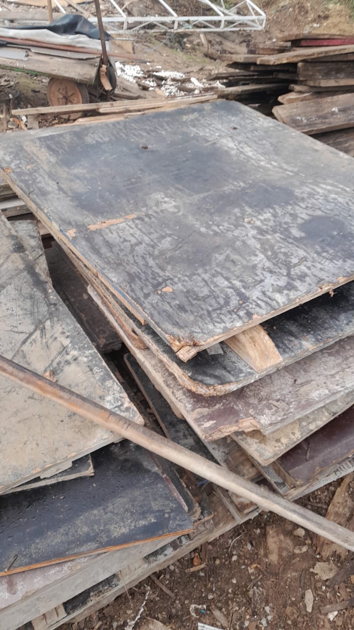 Pilha de chapas de compensado, formas e tábuas reaproveitadas de obra, estoque típico de material de construção para reutilização.