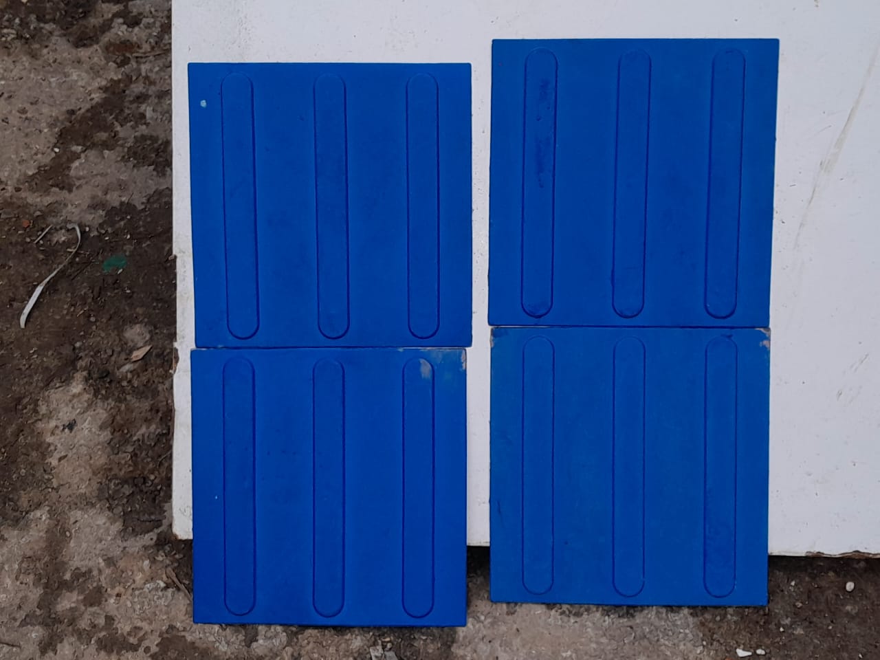 Quatro peças de piso tátil azul em relevo, material de construção civil reaproveitado disponível para venda.