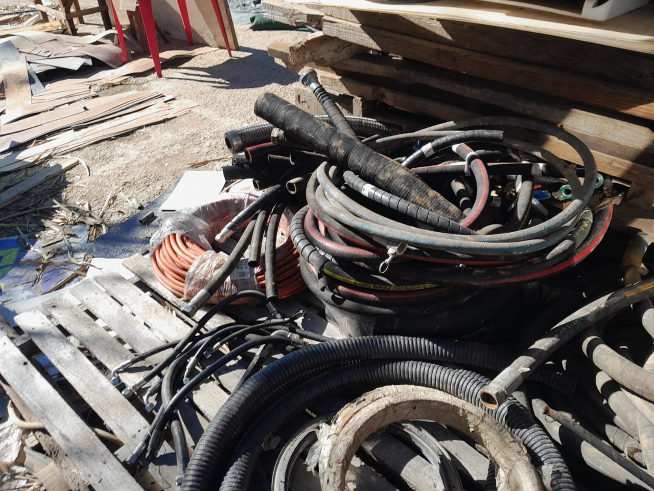 Pilha de mangueiras, cabos elétricos e materiais reaproveitados no pátio da loja, mostrando a diversidade de itens disponíveis para reutilização.